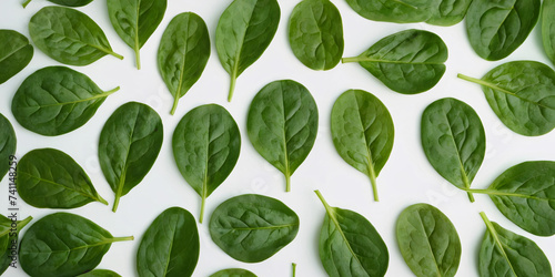 A harmonious arrangement of fresh, green spinach leaves against a pristine white background. The pattern created by the leaves exudes a sense of natural elegance and simplicity.