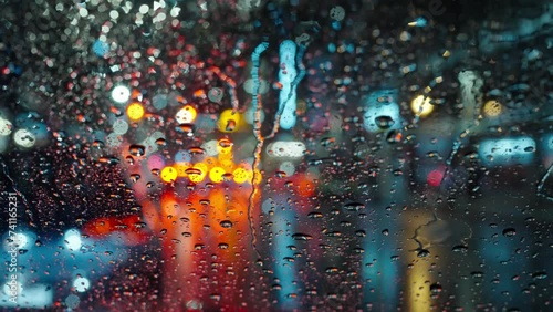 Lights of the evening city and passing cars through a wet rainy window.