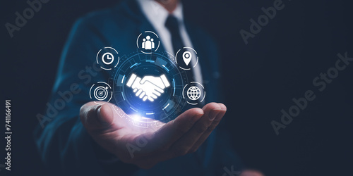 A businessman presents a holographic global partnership concept, with interconnected icons floating above his hand. Business partnerships concept. Business collaboration strategies.