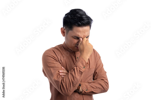 Unhealthy Asian Muslim man suffering from headache or migraine isolated on white background. Ramadan and Eid Fitr celebration concept © Sewupari Studio