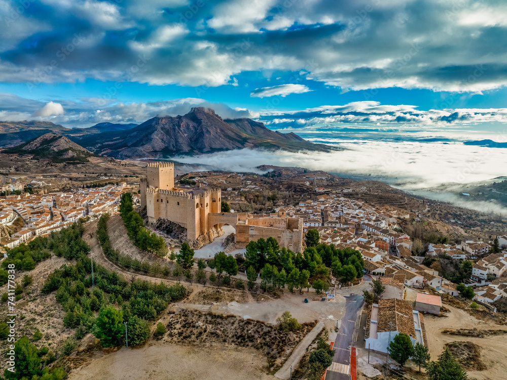 Aerial view of Velez Blanco hilltop medieval castle with square tower, restored Gothic palace above the town with dramatic sky - obrazy, fototapety, plakaty 