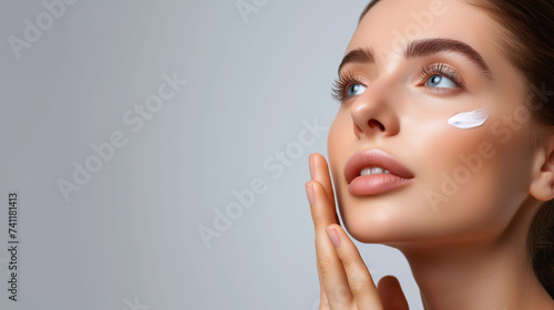 Woman applying moisturizer cream on face, skincare routine with space for text