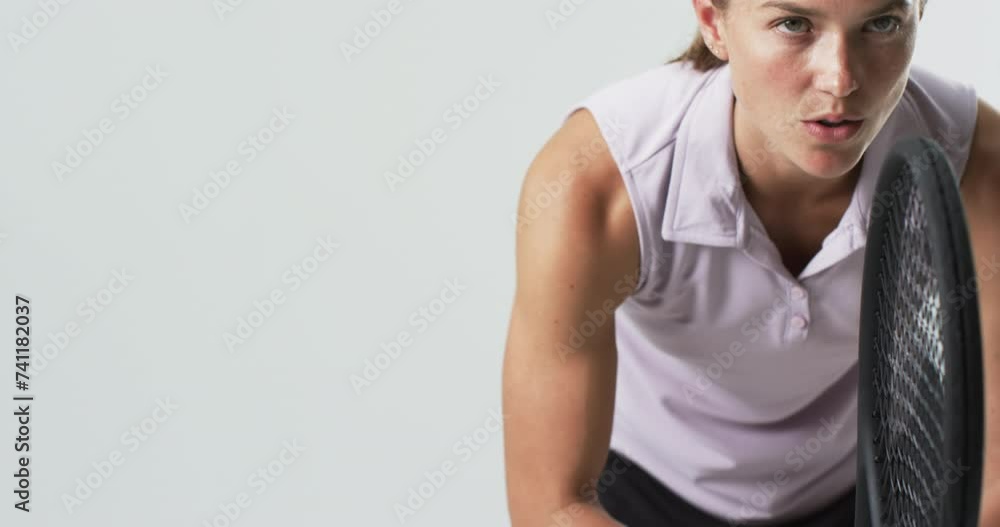 Focused young Caucasian woman prepares for a tennis match on a white background, with copy space Focused young Caucasian woman prepares for a tennis match on a white background, with copy space