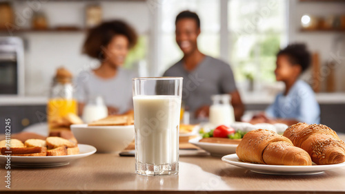 Delicious breakfast with croissants and milk on table in kitchen. Family with kids in background © Mariusz Blach