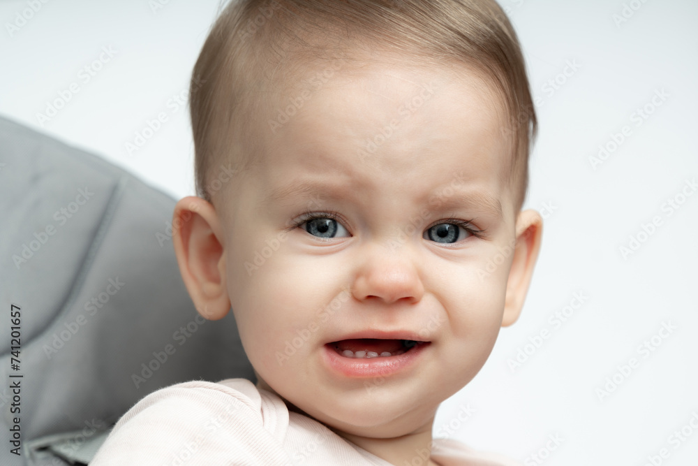 Portrait of crying 1-year old baby upset of being hungry and tired