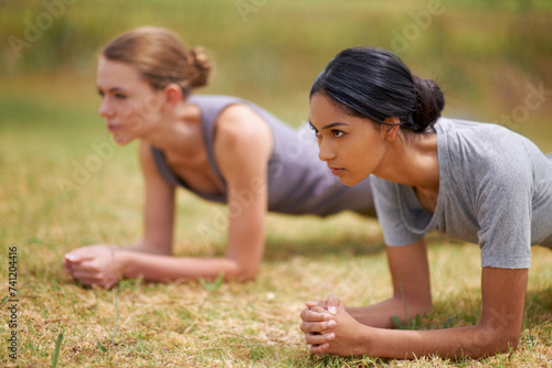Woman, friends and plank in fitness for core strength, exercise or outdoor workout on field in nature. Young female person or team in ab training for muscle, stamina or endurance on green grass