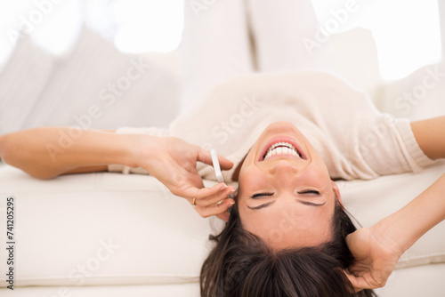Happy, phone call and woman upside down in home for conversation or communication with contact. Smartphone, funny or person laughing in living room to relax, joke or listening to comedy story on sofa