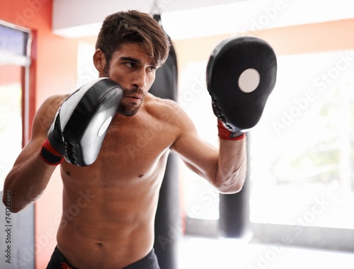 Gym, boxing and man with sparring pads for fitness, exercise and mixed martial arts training. Sports, fight and kickboxer with practise mitts for challenge, workout or gear for power, battle or focus photo