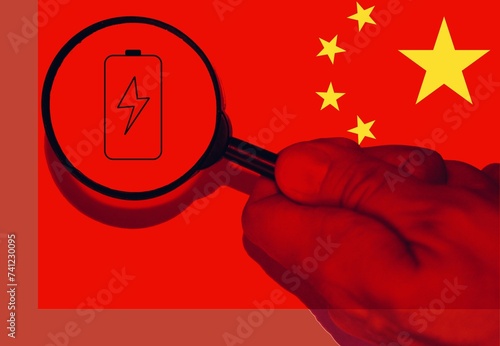 Photography Hand with a magnifier showing a battery with flag of China
