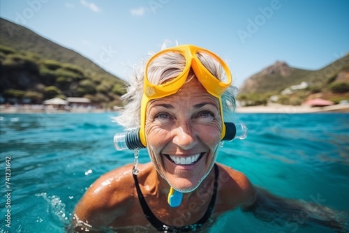 Portrait of happy senior woman snorkeling in the sea photo