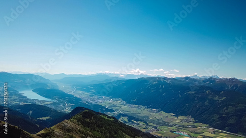 Idyllic hiking trail on alpine meadow with scenic view of lake Millstatt seen from mountain peak Boese Nase in Ankogel Group, Carinthia, Austria. Remote landscape in majestic Austrian Alps in summer photo