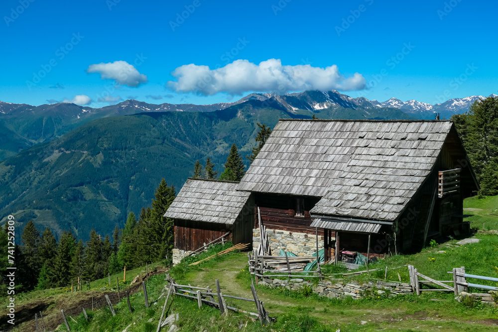 Wooden cottage with panoramic view of majestic mountain peaks of Carnic and Julian Alps. Idyllic hiking trail to Boese Nase, Ankogel Group, Carinthia, Austria. Remote Austrian Alps in summer. Alpine