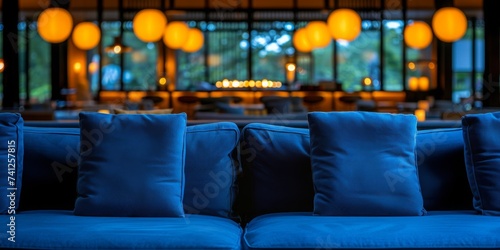 A Cozy Lounge Space with Deep Blue Sofas and Soft Pillows, Illuminated by Warm, Hanging Spherical Lights, Generative AI