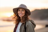 Portrait of a beautiful young woman with hat on the beach at sunset