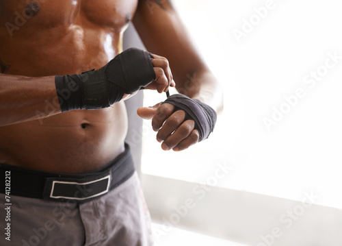 Hands, exercise and fighting with man wrapping at gym in preparation for training or combat sports. Fitness, mma or kickboxing with body of shirtless fighter getting ready closeup for martial arts photo