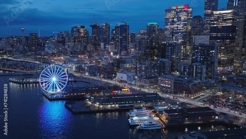 Aerial panorama of seafront and financial district skyscrapers and buildings, downtown Seattle at dark winter night light. 4K b roll drone shot of cityscape night scene. Illuminated night city USA