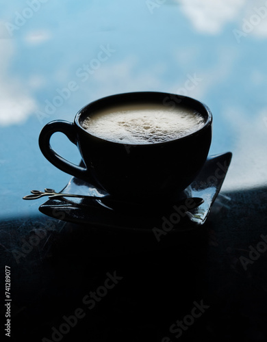 Cuppucino in silhouette against the sky reflexed on the table. Concept of The sky reflected in a coffee cup, offering a sip of the infinite photo