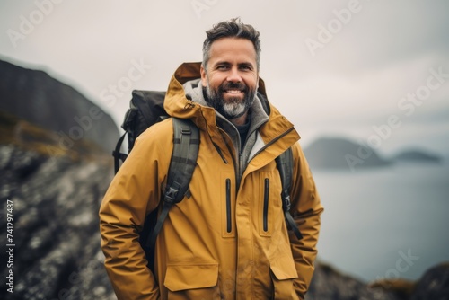 Handsome bearded man in a yellow jacket with a backpack on the background of the sea.