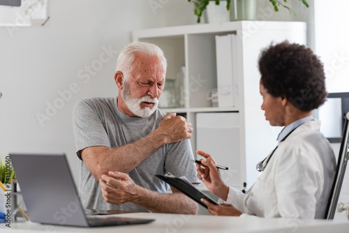 An African-American woman doctor specialist consults with an elderly male patient in her office