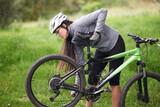 Fitness, bike and flat wheel with woman cyclist in countryside for sports, hobby or cardio training. Exercise, cycling or tyre puncture with young athlete fixing bicycle outdoor in nature for workout
