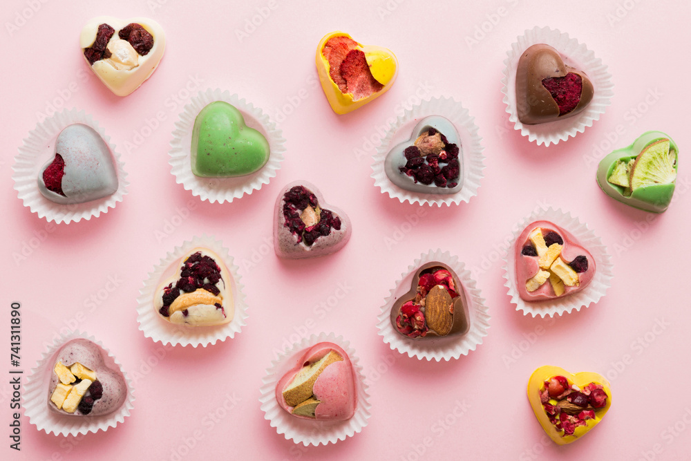 chocolate sweets in the form of a heart with fruits and nuts on a colored background. top view with space for text, holiday concept