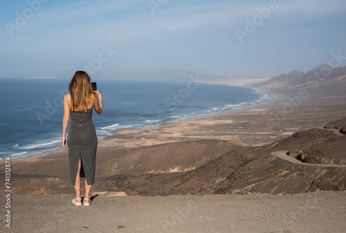 Chica sacando una foto con el telefono des del mirador de la playa de Cofete © jordirenart