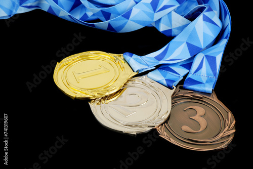 Gold, silver and bronze medal with ribbons isolated on black.
