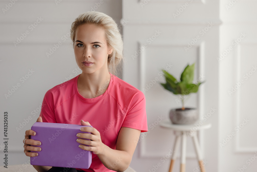Beautiful young sporty woman having morning training with foam yoga brick Beautiful young sporty woman having morning training with foam yoga brick