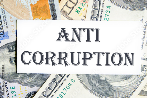 ANTI CORRUPTION text writing on a white card against the background of banknotes photo