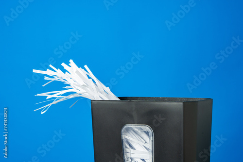 Office paper shredder on blue studio background photo