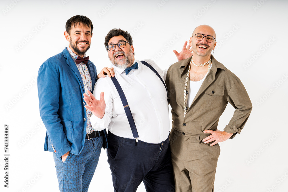 Three Smiling Queer Men Posing Together in Stylish Outfits Against White Background Three Smiling Queer Men Posing Together in Stylish Outfits Against White Background