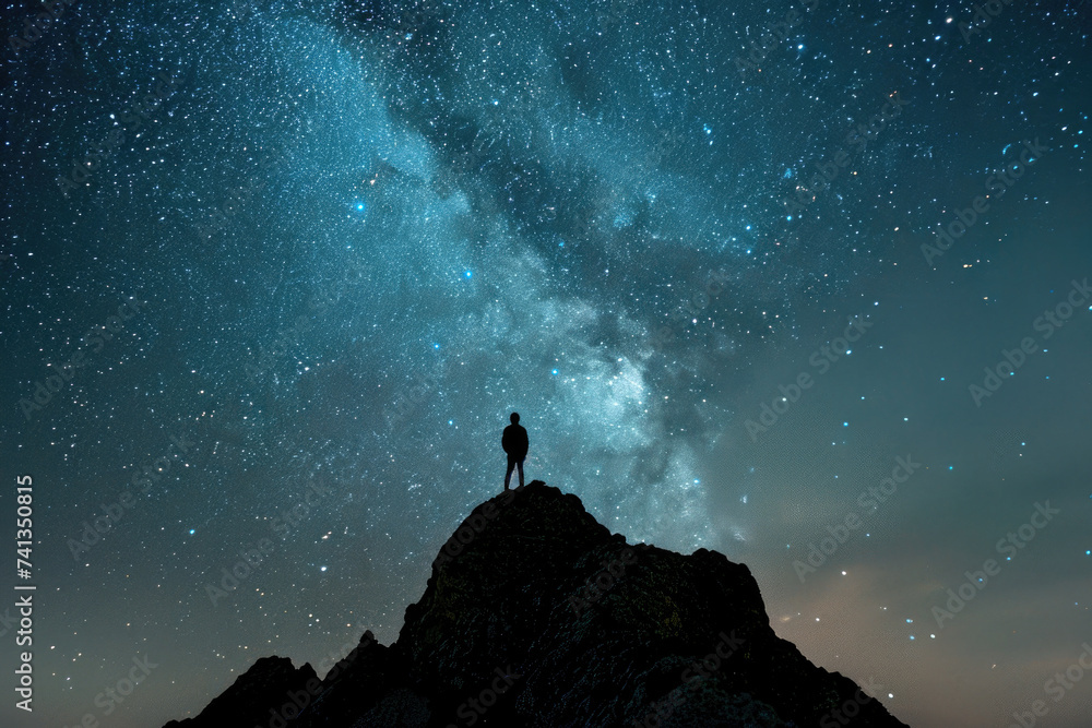 A silhouette of a person stargazing on a mountaintop