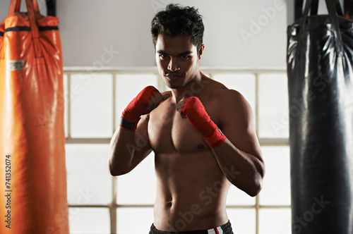 Portrait, man and boxing in club for sports, training and workout for healthy body. Fighter, face and serious athlete with muscle on abs for fitness, exercise and martial arts at a gym in Brazil