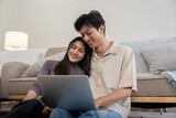 Happy couple asian with laptop on floor in the living room at home