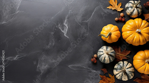 A group of pumpkins with dried autumn leaves and twig, on a dark gray color marble
