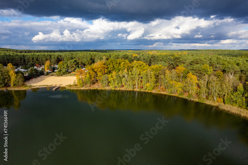 Aerial shot of beautiful lake surrounded by forest in a calm autumn day. Germany.