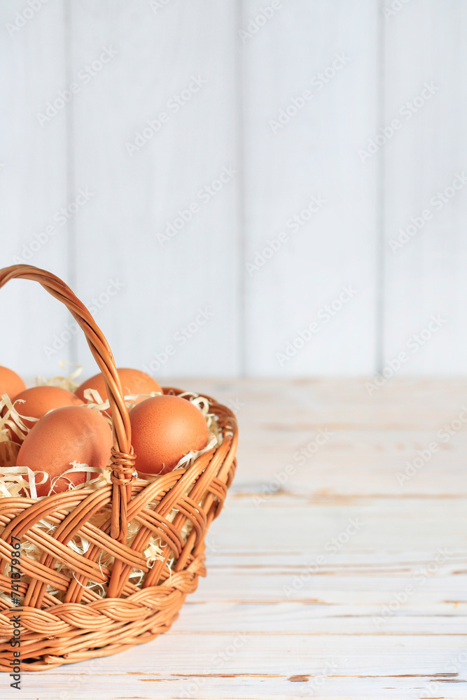 Eggs in a wicker basket on a white wooden table, copy space. Eggs in a wicker basket on a white wooden table, copy space.