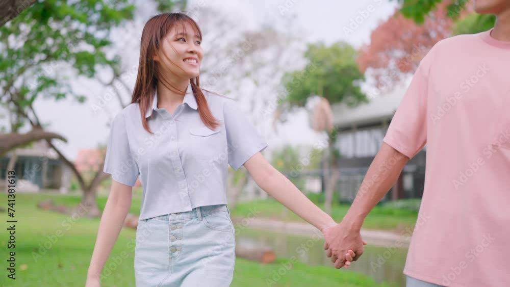 A married couple chatting happily and walking hand in hand outdoors in the city green space enjoying sightseeing together on the road. marriage relationship A married couple chatting happily and walking hand in hand outdoors in the city green space enjoying sightseeing together on the road. marriage relationship