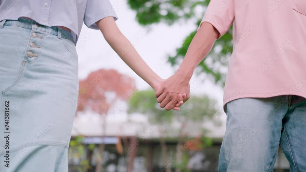 Close-up of a man looking back, trusting, holding hands, enjoying, relaxing, walking, forward into the sunlight. With an Asian woman in a field of nature begins the family's dream of a life of love, Close-up of a man looking back, trusting, holding hands, enjoying, relaxing, walking, forward into the sunlight. With an Asian woman in a field of nature begins the family's dream of a life of love,