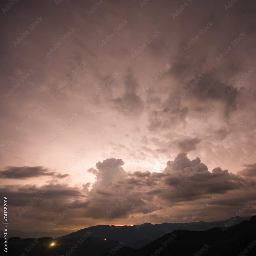 Evening thunderstorm with lightning in the mountains. Dramatic clouds during a thunderstorm pierce the light of lightning in a mountainous area.