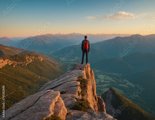 A man on top against the backdrop of a mountain valley at sunset