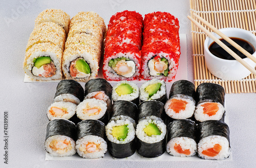 Popular types of sushi, soy sauce and chopsticks. Set of sushi roll on a gray background.