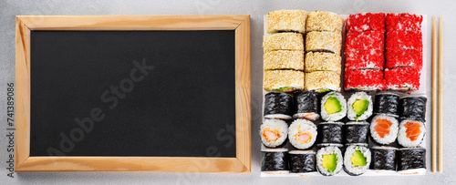 Popular types of sushi. Set of sushi roll on a gray background. Empty black chalkboard. Top view.