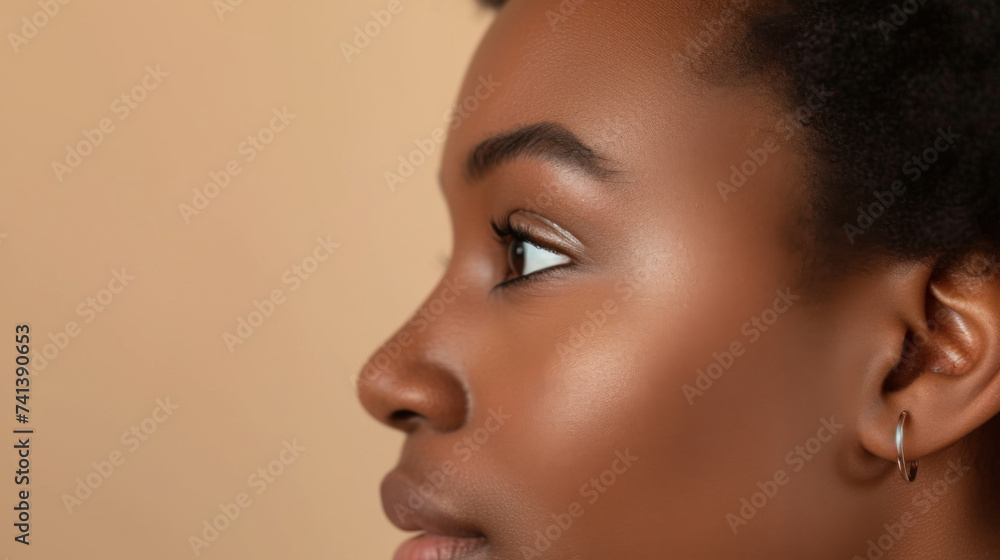 Close-up profile portrait of a young woman wearing an earring. Model face dark-skinned girl with copy space on a beige background. Close up of the face of a black African American woman. Close-up profile portrait of a young woman wearing an earring. Model face dark-skinned girl with copy space on a beige background. Close up of the face of a black African American woman.