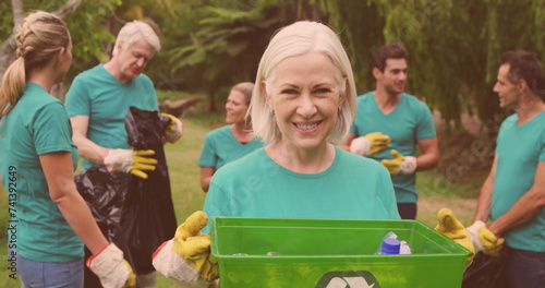 Image of happy diverse group picking up rubbish in countryside