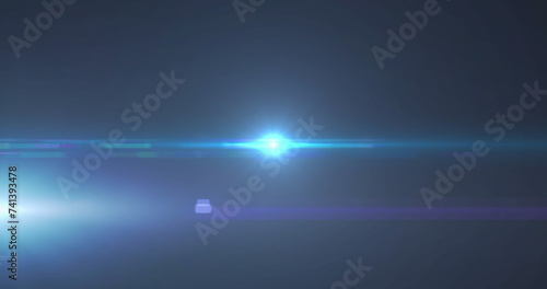 Image of blue spotlight with lens flare and light beams moving over dark background © vectorfusionart