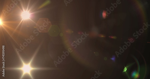 Image of spotlight with lens flare and light beams moving over dark background photo