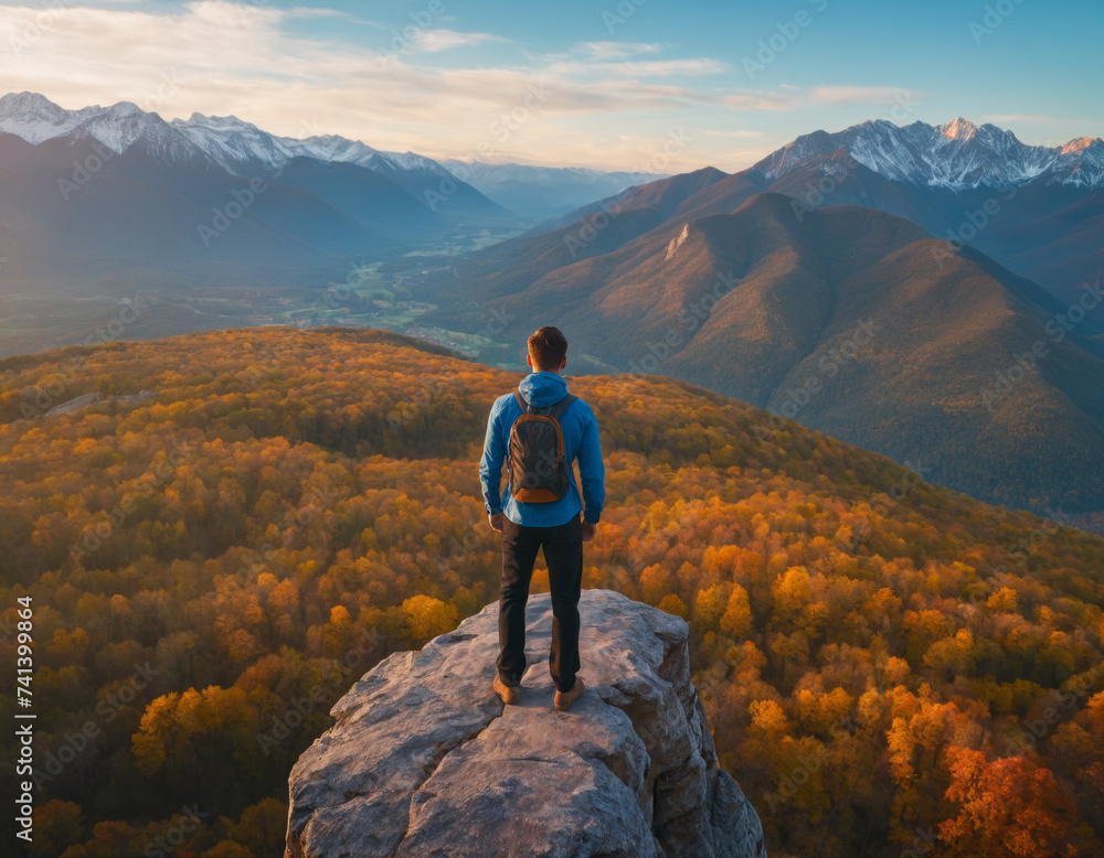 A man on top against the backdrop of a mountain valley at sunset