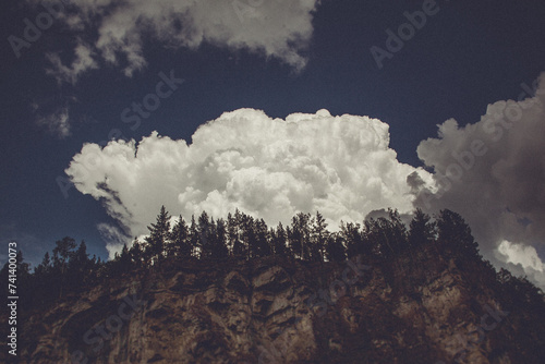 A cumulus cloud hovers above a treecovered mountain in the natural landscape photo