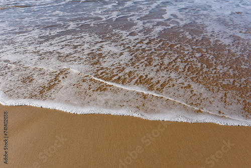 Canvas-taulu Espuma de mar  sobre la arena mojada en la orilla de una playa.